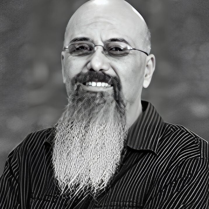 Man with glasses and long beard smiling.