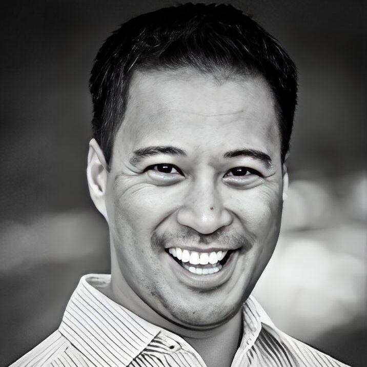 Smiling man in black and white portrait.