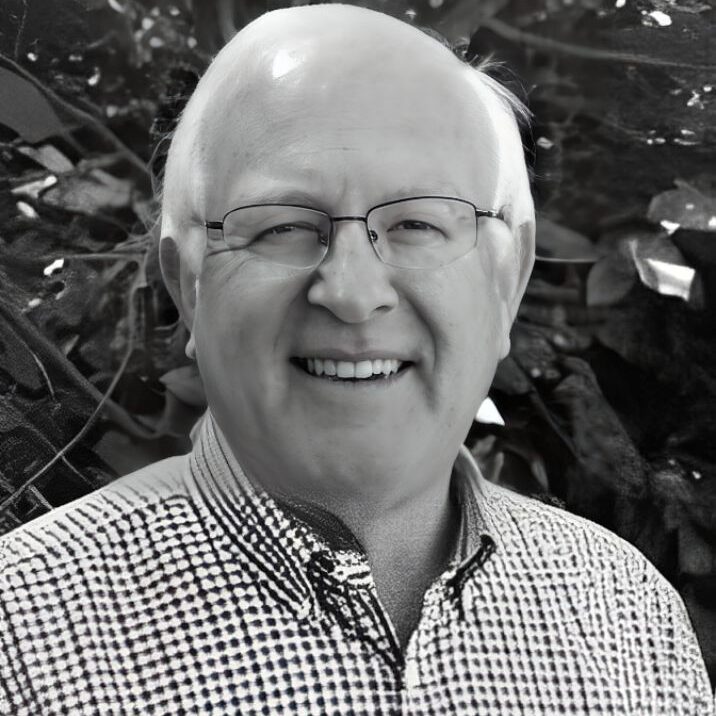 Smiling man with glasses, checkered shirt.