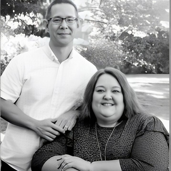 Smiling couple posing outdoors, black and white.
