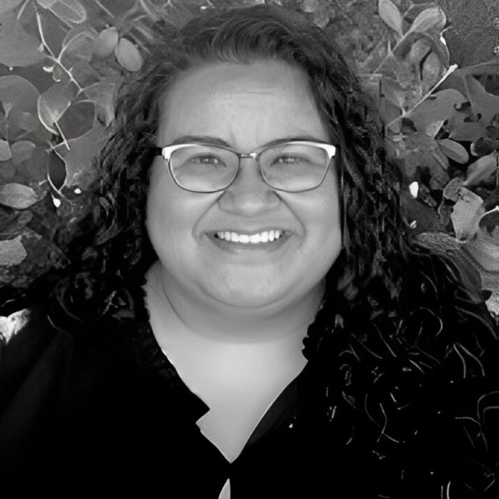 Smiling person with glasses and curly hair.
